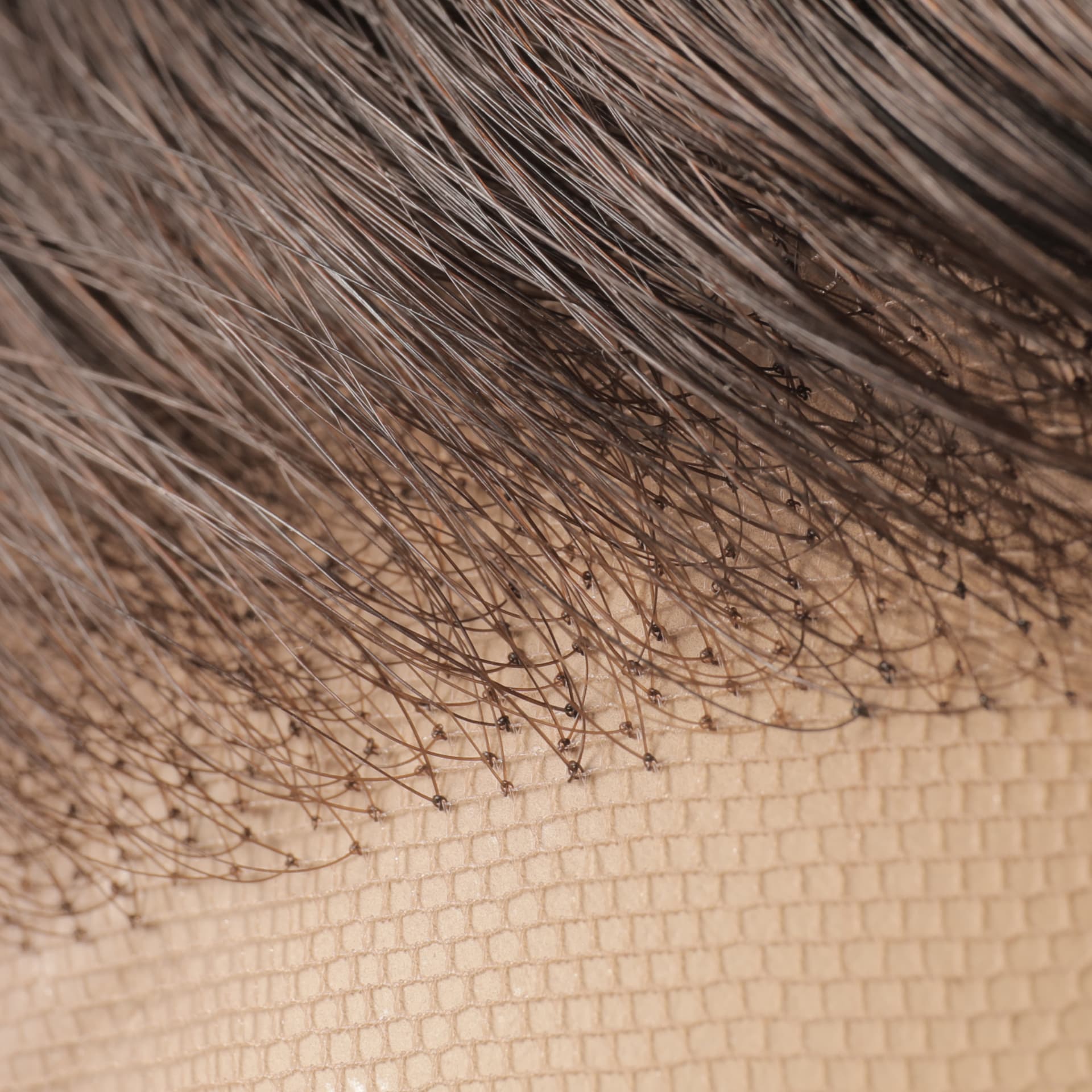 Close-up of hand-tied knots in fine Swiss lace on a GOLDWIGS wig base